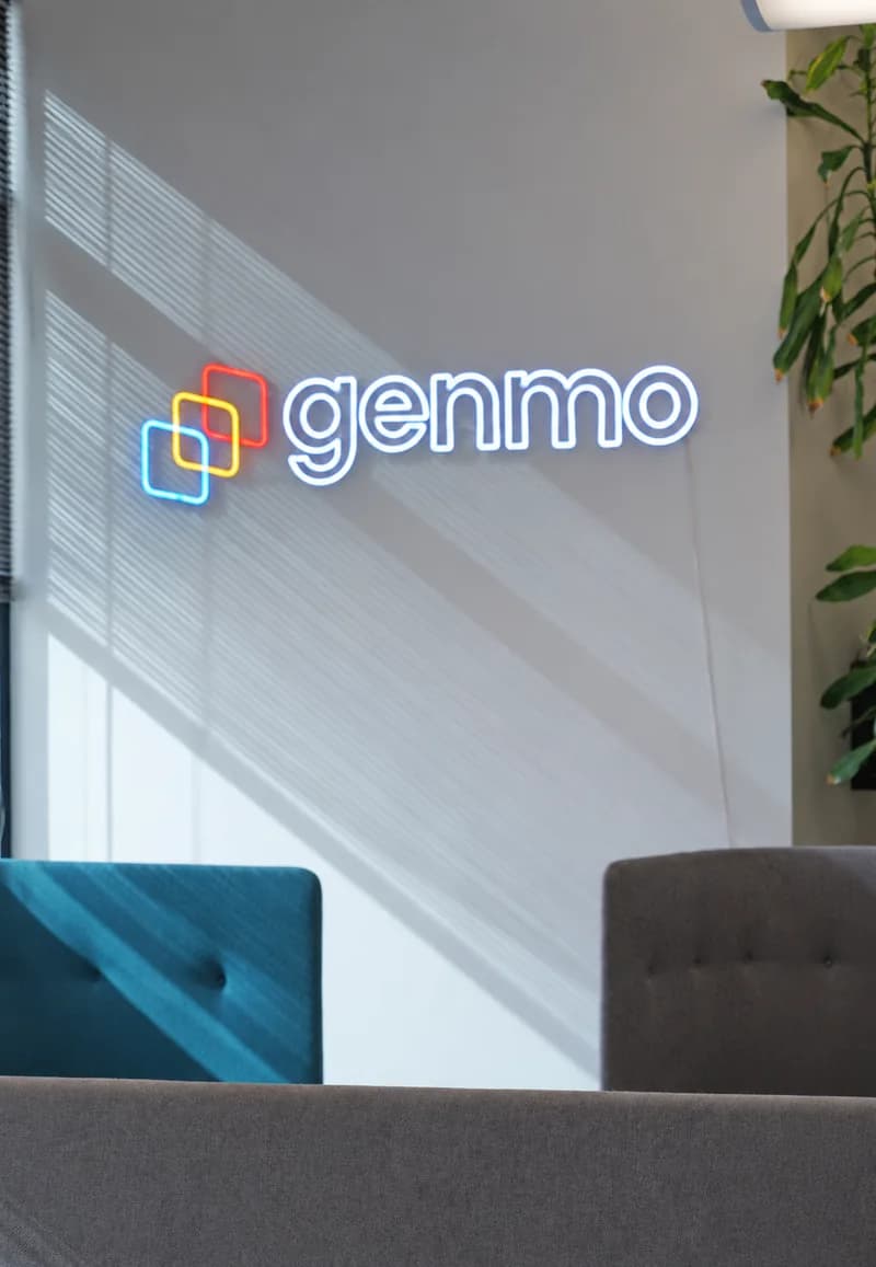Illuminated Genmo sign beside lounge chairs
